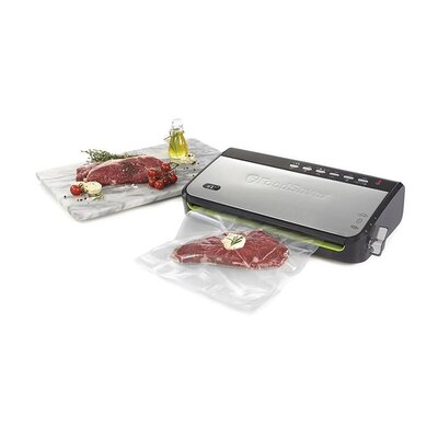 Vákuová balička potravín FoodSaver FFS005X s čerstvým mäsom vo vákuovacom sáčku na kuchynskej doske vedľa koreninového oleja a paradajok.