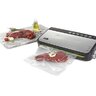 Vákuová balička potravín FoodSaver FFS005X s čerstvým mäsom vo vákuovacom sáčku na kuchynskej doske vedľa koreninového oleja a paradajok.